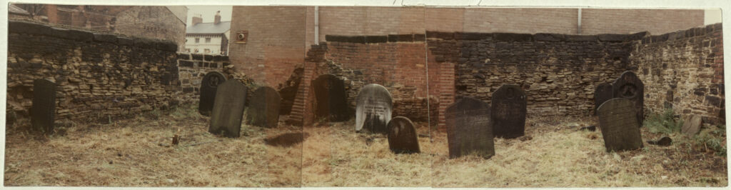 A panoramic photograph of gravestones in a walled area.