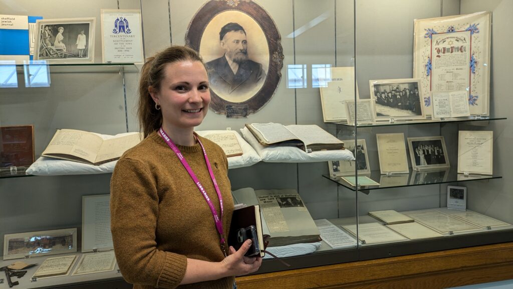 A woman standing by a display of archive documents in a large exhibition case.