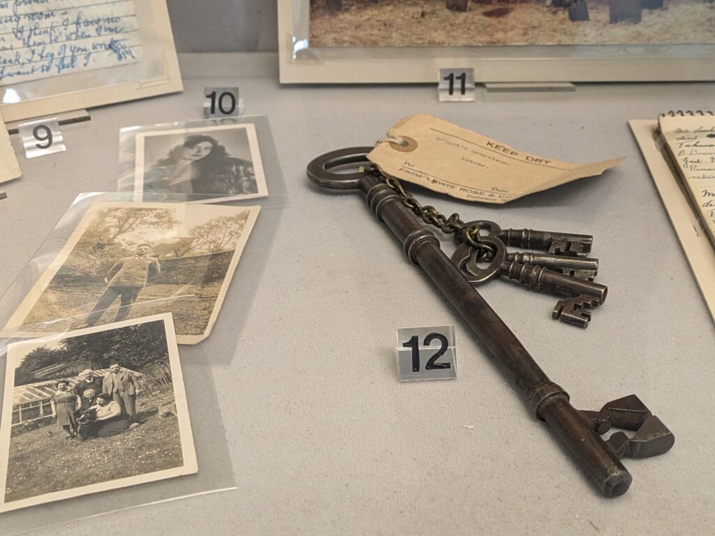 Three black and white photographs from various times in history on display next to one large and three small iron keys.