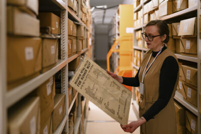 Hands wearing blue gloves turning the pages of a book