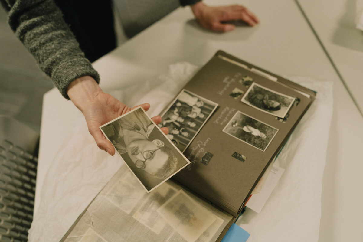 An open photo album with someone showing the camera one of the black and white photographs