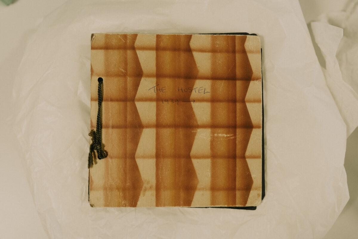 A patterned, square book with the words 'The Hostel' written on it.