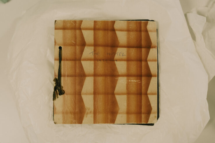 A patterned, square book with the words 'The Hostel' written on it.