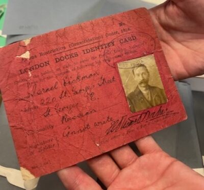 A red identity card with a photograph of a man with a moustache