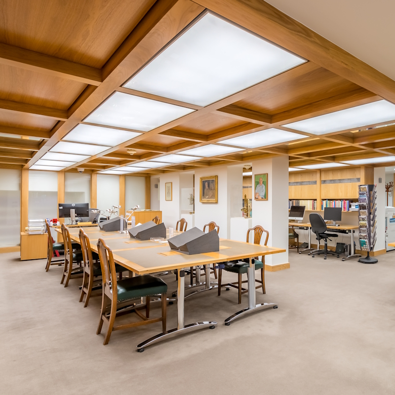 A wide and bright room with desks located in a library.